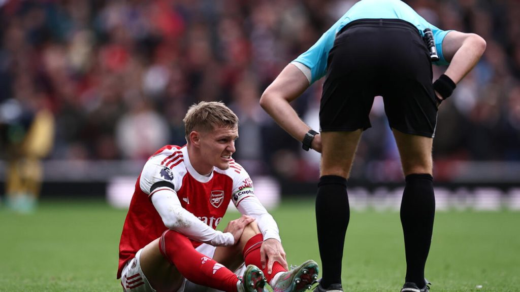 football player sitting on the pitch complaining to the referee about a possible injury