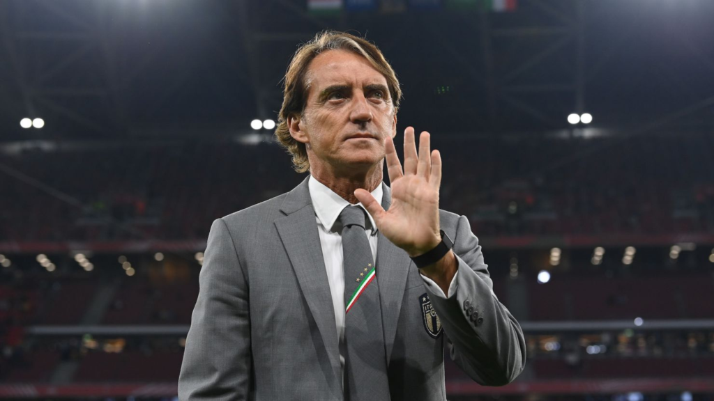 Roberto Mancini holding his hand up while looking the other way