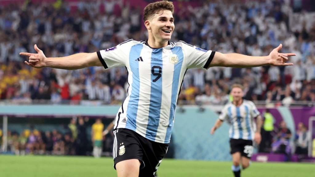 Julian Alvarez, arms wide, celebrating a goal for Argentina with a smile on his face