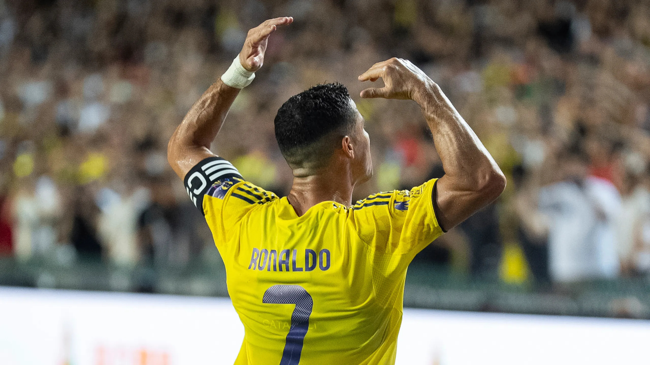 Backview of Cristiano Ronaldo with his hands up in the air and playing for Al Nassr