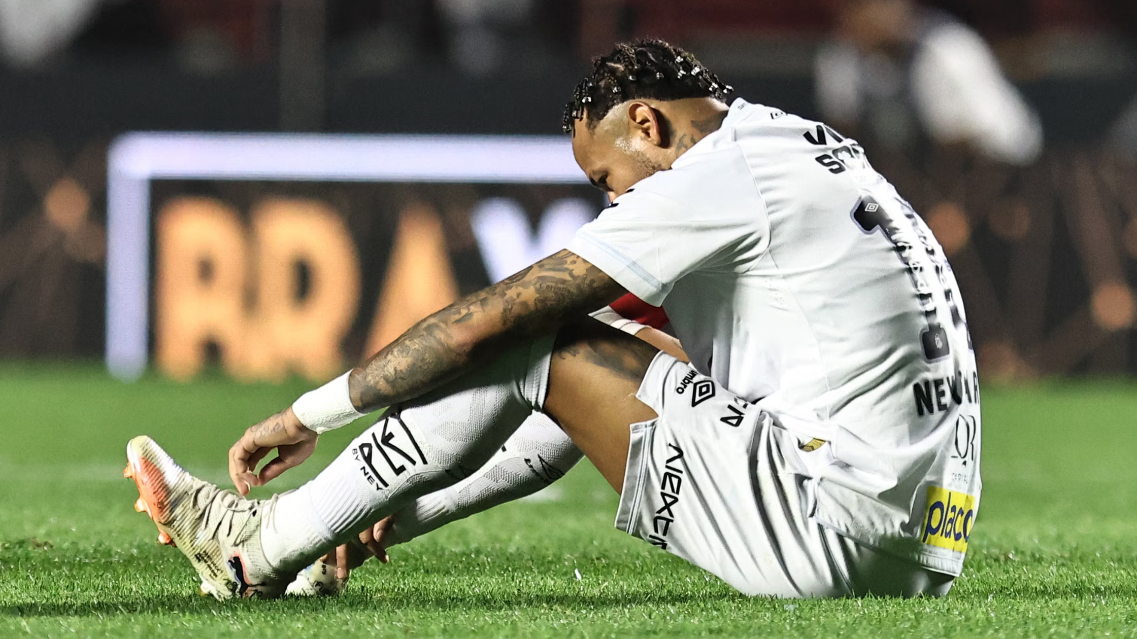 Sideview of Neymar sitting on the pitch for Santos