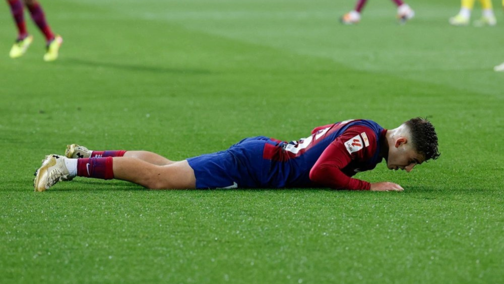 Fermin Lopez laying on his stomach on the pitch while playing for Barcelona