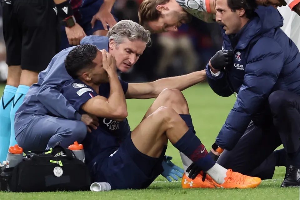 Achraf Hakimi laying on the pitch, injured, as he breaks down in tears, with the medical team around him