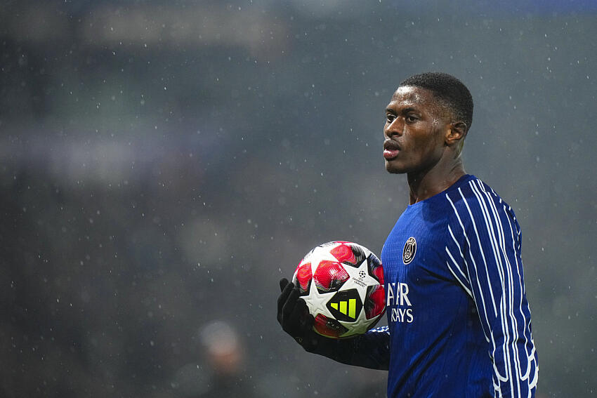 Nuno Mendes holding the ball on a rainy night in a psg shirt