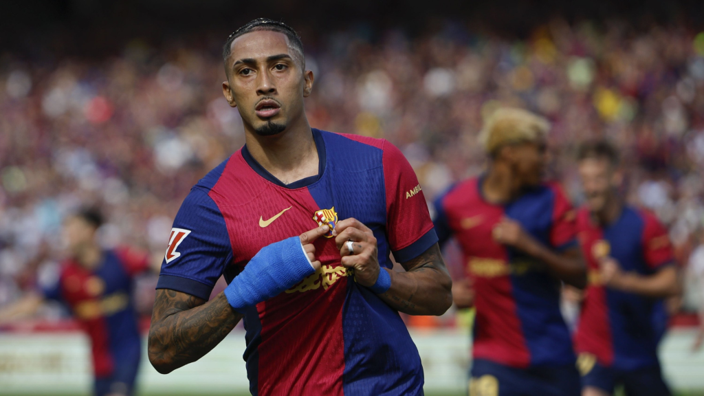 Raphinha pointing to the Barca badge as a Barcelona player