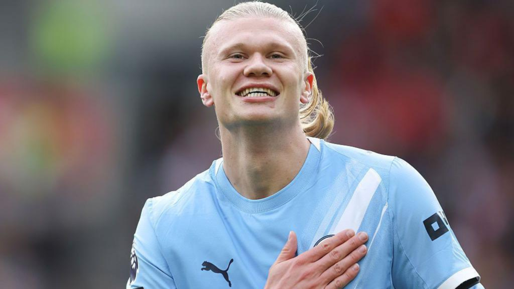 Frontview of Erling Haaland patting the Man City badge