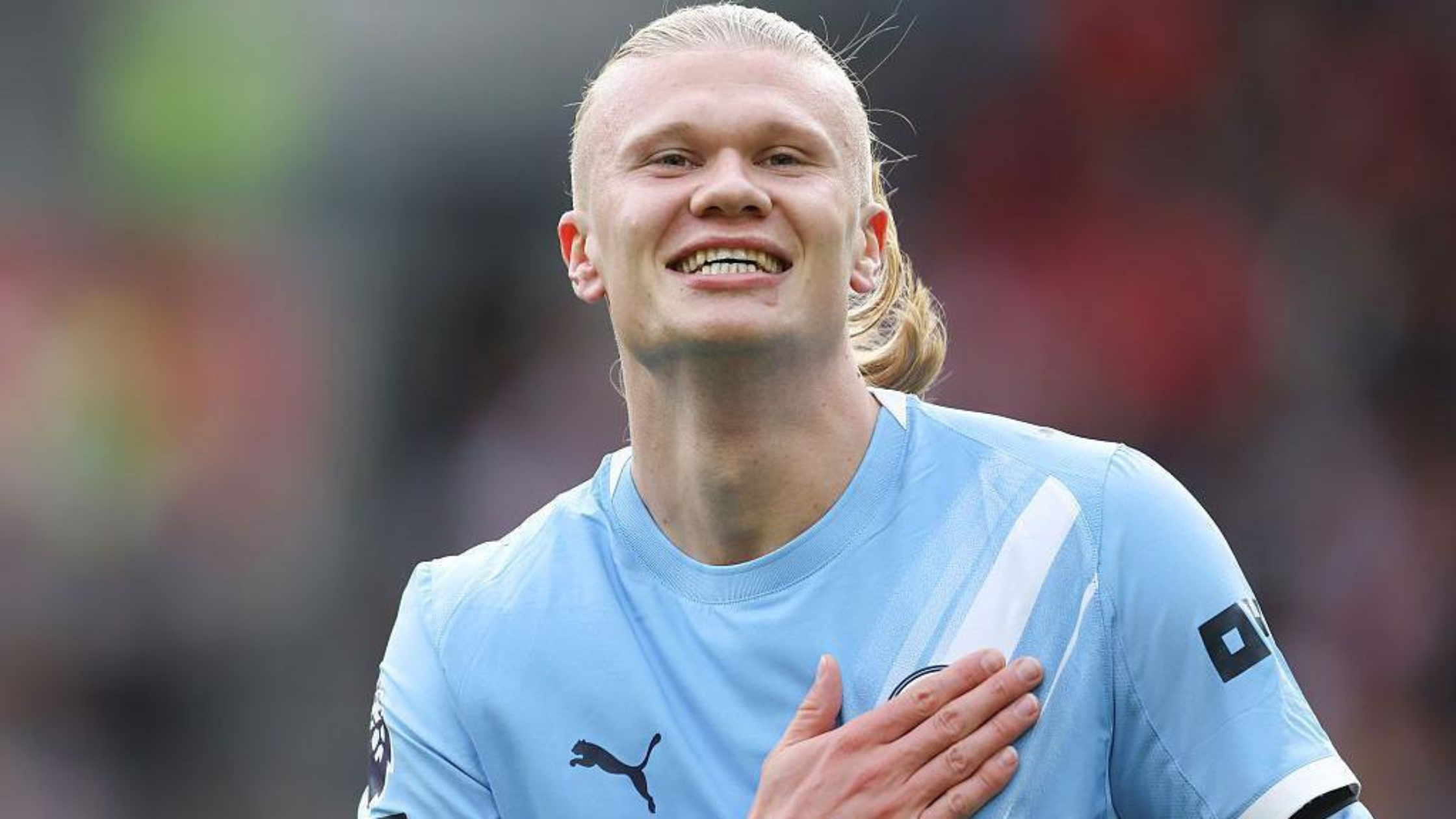 Frontview of Erling Haaland patting the Man City badge