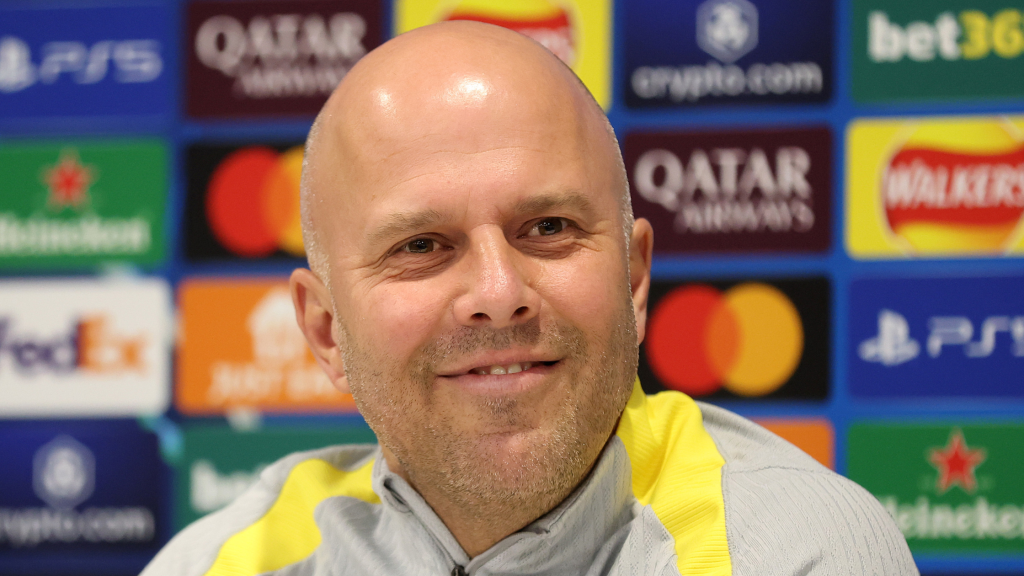 Арне Слот на прес-конференција пред натпревар, со позадина од спонзори